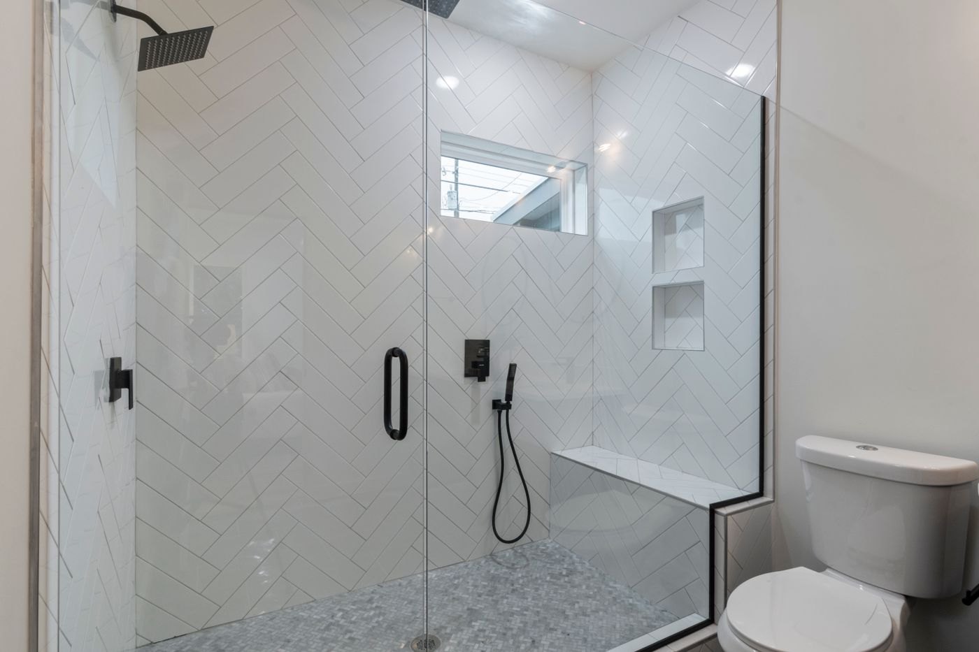 Low-threshold walk-in shower with glass panel and built-in bench